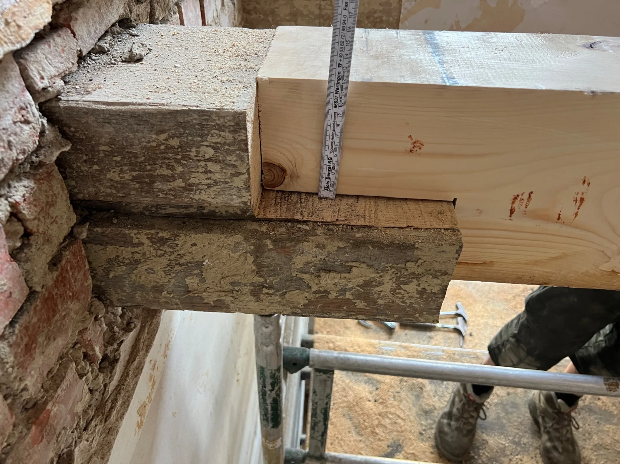 Detail eines freigelegten Holzbalkens in einer Mauerwerksöffnung während der Bestandssanierung.
