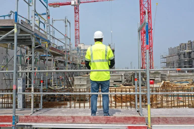 Person mit MSA-Warnjacke bei der Überwachung einer Baustelle.